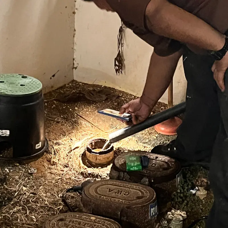 A Barrett plumber clearing a sewer cleanout at night