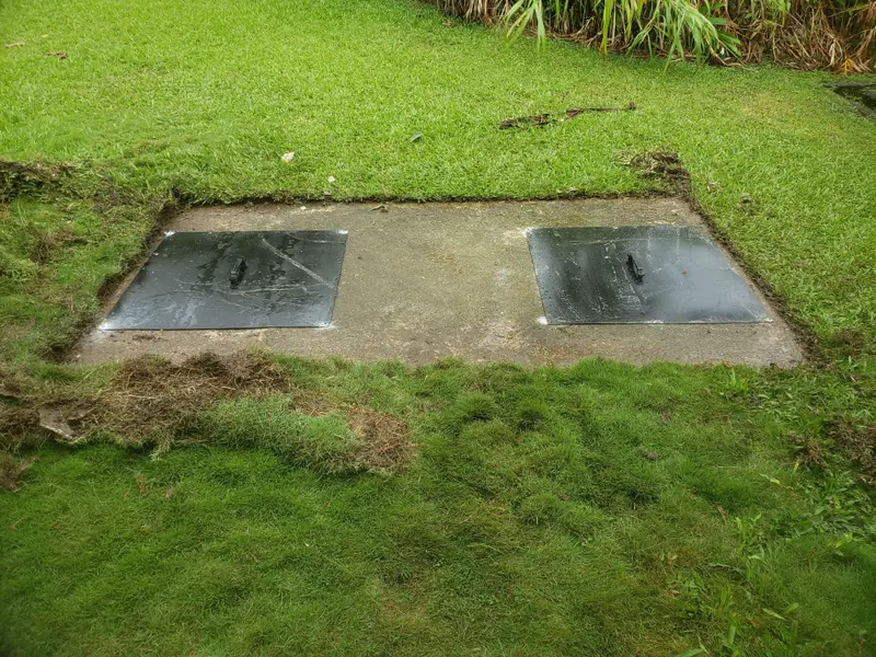 Two new septic tank lids set in a concrete pad in the lawn