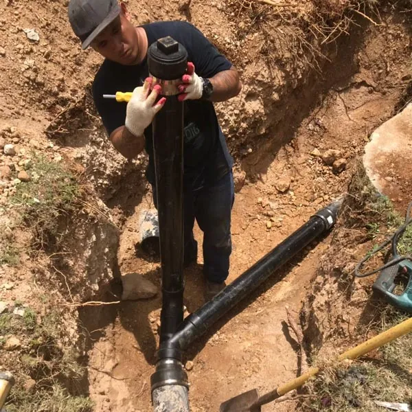Barrett crew member fitting a black sewer pipe in an open trench